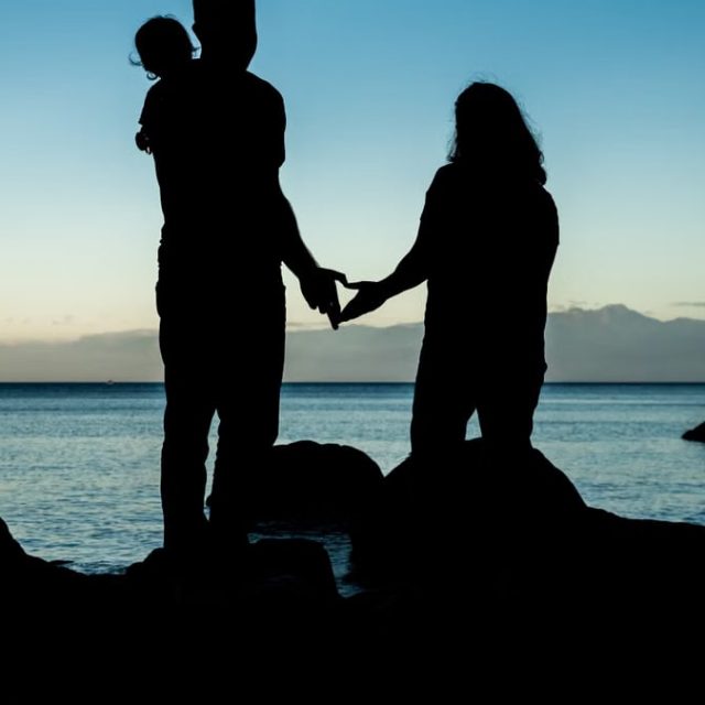 A family silhouette enjoys the serene sunset at Metchosin Beach, Canada.
